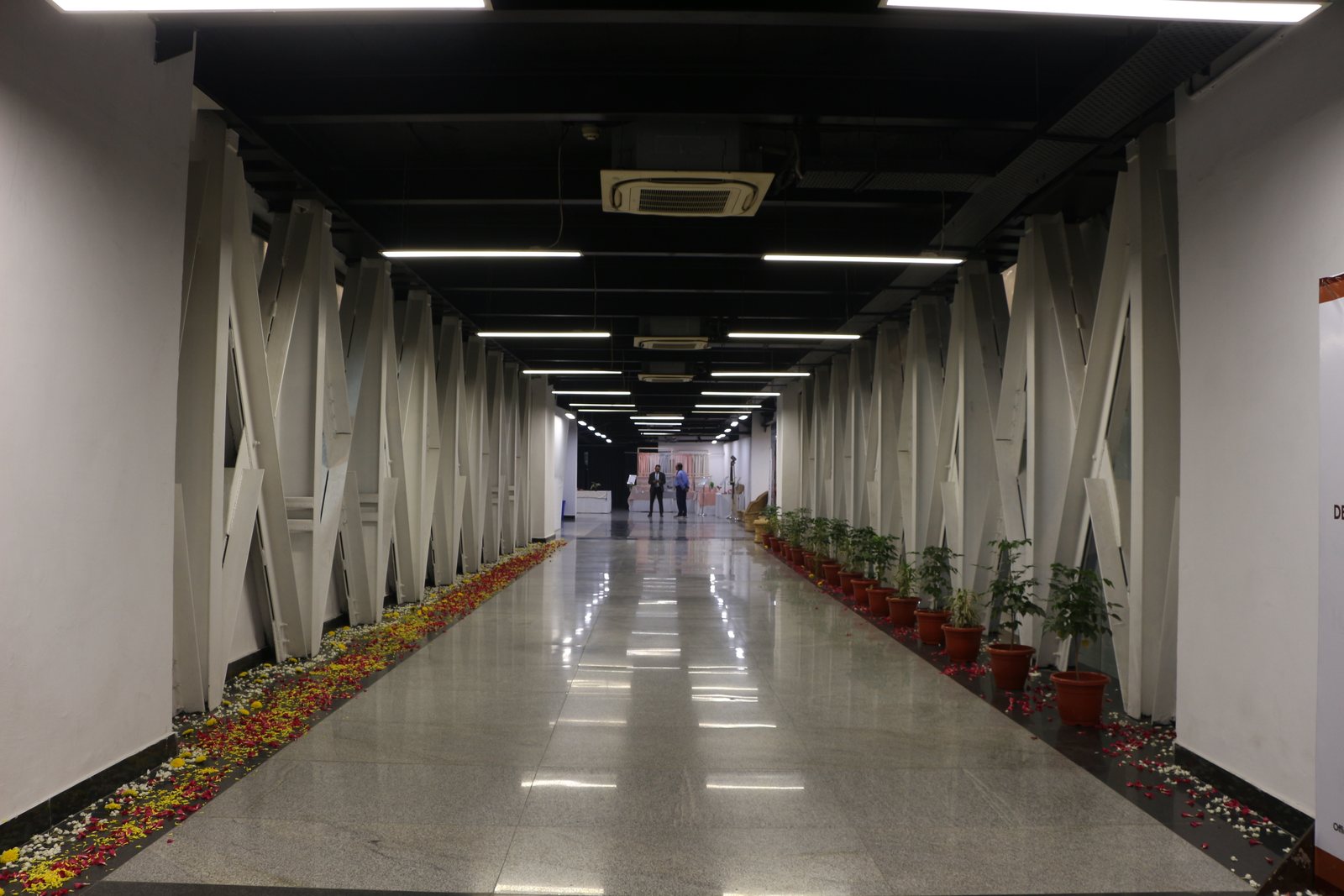 Wide passageway with white fabric curtain panels suspended on both sides linearly.