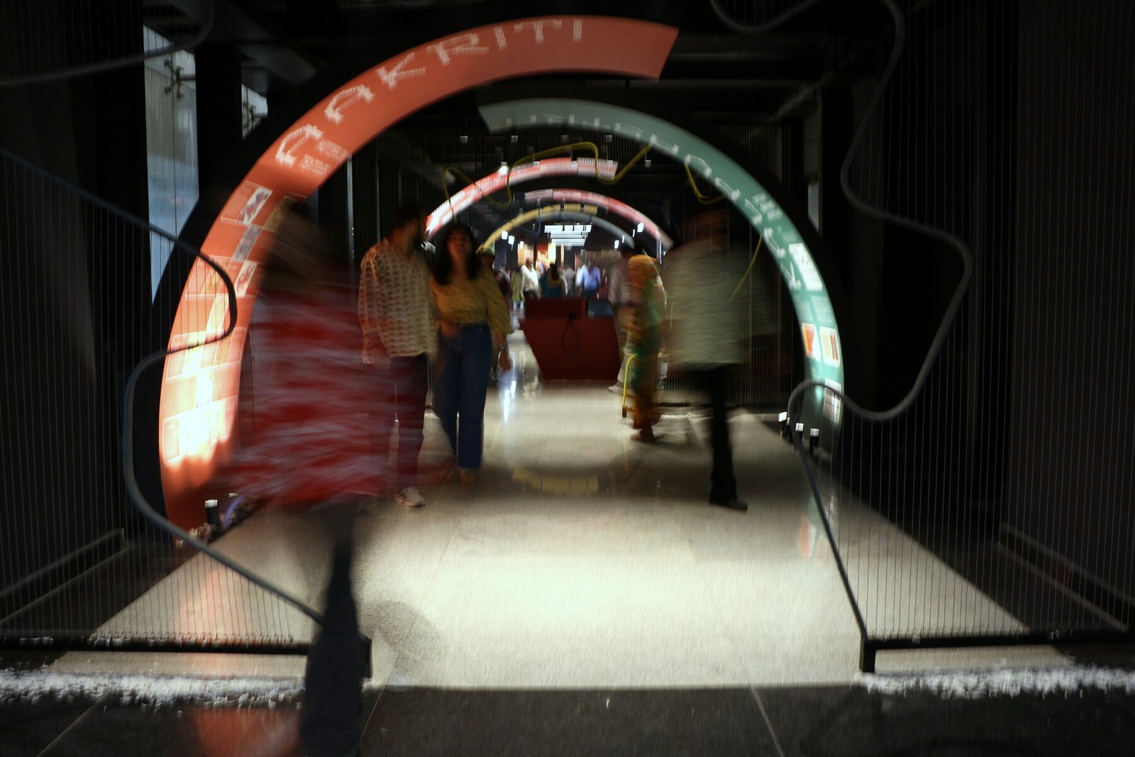 Visitors walk beneath a run of colourful lettered arches.
