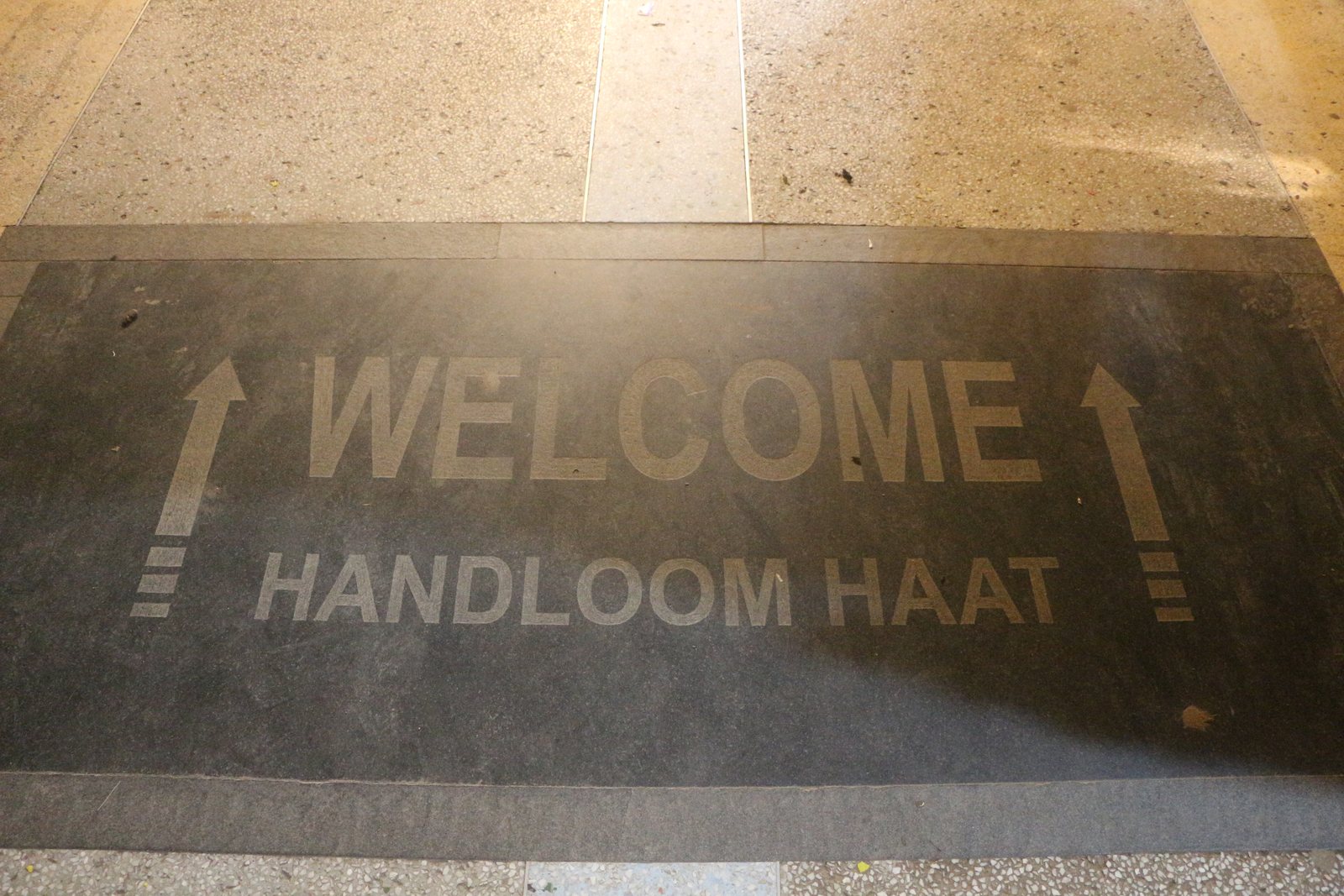 Gallery floor entrance with Welcome Handloom Haat text and polished stone flooring.